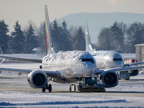 An Air Canada aircraft covered with snow and ice is moved by a tug as a Westjet aircraft is seen being moved behind it at Vancouver International Airport in Richmond, B.C., on Wednesday, Dec. 21, 2022. The airport is limiting international flights to carriers registered in Canada and the U.S. for two days as it attempts to clear a backlog of aircraft and passengers after a snowstorm caused massive disruptions this week.