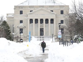 Gerald Crosby walks down a sidewalk surrounded by snow on University at Buffalo campus in Buffalo, N.Y., on Tuesday, Dec. 27, 2022. This comes days after a blizzard hit four Western New York counties.