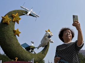 A woman takes a souvenir photo with a floral decoration featuring China's space programs celebrating National Day and the 20th party congress in Beijing on Sept. 26, 2022. The U.S. is closely monitoring Chinese activities that potentially threaten American assets in space and is deeply concerned about the rapidly accumulating amount of space debris in low earth orbit, the head of United States military operations in space said Friday, Dec. 9, 2022.