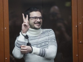 Russian opposition activist and former municipal deputy of the Krasnoselsky district Ilya Yashin gestures, smiling as he stands inside a glass cubicle in a courtroom, prior to a hearing in Moscow, Russia, Friday, Dec. 9, 2022. Yashin faces a trial on charges stemming from his criticism of the Kremlin's action in Ukraine.