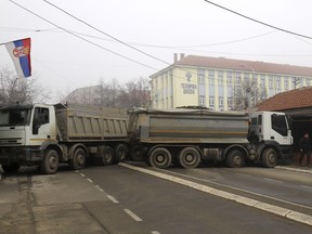 A man passes by a barricade made of trucks loaded with stones that was erected during the night on a street in northern, Serb-dominated part of ethnically divided town of Mitrovica, Kosovo, Tuesday, Dec. 27, 2022. Serbia on Monday placed its security troops on the border with Kosovo on "the full state of combat readiness," ignoring NATO's calls for calming down of tensions between the two wartime Balkan foes.
