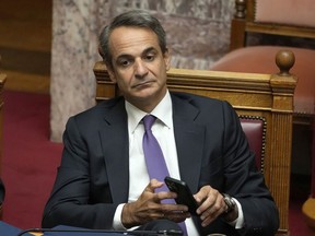 FILE - Greece's Prime Minister Kyriakos Mitsotakis holds his cellphone during a parliament session in Athens, Greece, Friday Aug. 26, 2022. Lawmakers in Greece on Thursday, Dec. 8, 2022 were debating draft legislation to outlaw commercial spyware following weeks of allegations that senior government officials may have been targeted.