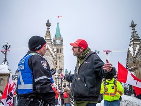Chris Dacey, who attended Saturday's event, makes his point to an Ottawa Police Service liaison officer after a disagreement with city bylaw officers on Wellington Street.