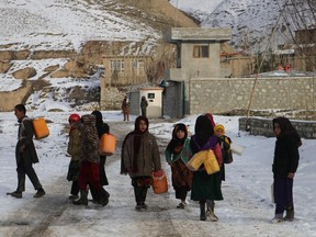 Children carry containers to fetch drinking water along a road during a cold winter day in Yaftal Sufla district of Badakhshan Province on January 18, 2023.