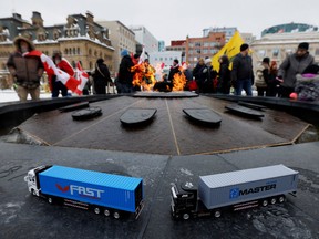 Toy trucks seen on the Centennial Flame on Saturday as demonstrators gathered on Parliament Hill to mark the first anniversary of Freedom Convoy's blockade of Ottawa in protest of Trudeau government vaccine mandates.
