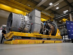 An employee of Siemens Energy stands on August 3, 2022 next to a turbine of the Nord Stream 1 pipeline at the plant of Siemens Energy in Muelheim an der Ruhr, western Germany, where the engine is stored after maintenance work in Canada.