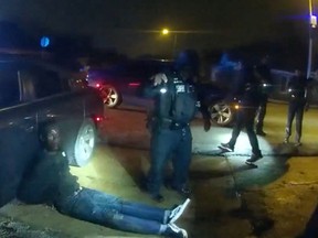 A beaten Tyre Nichols sits handcuffed on the ground surrounded by police officers in an image from a Memphis Police Department bodycam video released on January 27, 2023.