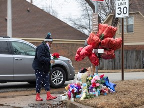 Talesha Vester prepares to place flowers at a memorial for Tyre Nichols at the intersection of Castlegate Lane and Bear Creek Cove in Memphis, Tenn., 
 on Jan. 30, 2023.