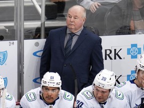 Vancouver Canucks coach Bruce Boudreau stands behind the bench during the first period of the team's NHL hockey game against the Pittsburgh Penguins in Pittsburgh, Tuesday, Jan. 10, 2023. Boudreau got emotional when asked about his future with the organization during a media scrum following the team's morning skate on Friday.