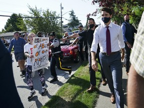 Liberal Leader Justin Trudeau walks past protesters in Surrey, B.C., on August 25, 2021.