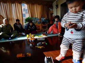 Tang Huajun, Ang Ran and her parents sit near their 2-year-old son Tang Ziang at their home in Beijing, China Nov.8, 2022.