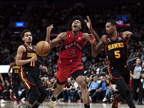 Toronto Raptors forward Scottie Barnes (4) draws a foul while guarded by Atlanta Hawks guard Dejounte Murray (5) and guard Trae Young (11) during first half NBA basketball action in Toronto on Saturday, January 14, 2023.