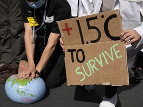 FILE - Demonstrators pretend to resuscitate the Earth while advocating for the 1.5 degree warming goal to survive at the COP27 U.N. Climate Summit, Nov. 16, 2022, in Sharm el-Sheikh, Egypt. A new study using artificial intelligence finds that the world will likely warm a few more tenths of a degrees within the next 10 to 12 years and breach a key climate change threshold aimed at limiting the worst effects of climate change.
