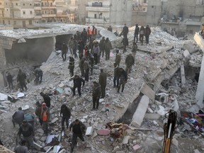 In this photo provided by Kurdish-run Hawar News Agency, civil defense workers and civilians work on the rubble of a destroyed building in the Sheikh Maksoud neighborhood in Aleppo, Syria, Sunday, Jan. 22, 2023. The building collapsed in Aleppo early Sunday, killing at least 10 people, Syrian state media reported. (Hawar News Agency via AP)