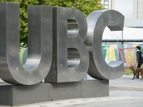 A woman and her dog walks past the UBC sign at the University of British Columbia in Vancouver, on April 23, 2019. The University of British Columbia says it deeply regrets its handling of the case of retired judge and former law professor Mary Ellen Turpel-Lafond, who was the subject of a CBC investigation about her claims of Indigenous heritage.