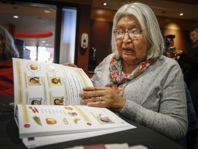 Stoney Nakoda elder Winnfred Beaver scans through a new textbook of the Stoney language aimed at preserving the Indigenous language at a ceremony in Kananaskis, Alta., on Monday, Jan. 23, 2023.THE CANADIAN PRESS/Jeff McIntosh