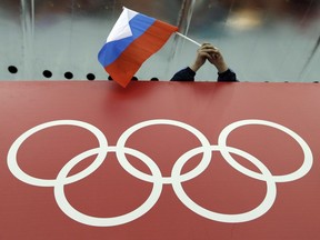 FILE - A Russian flag is held above the Olympic Rings at Adler Arena Skating Center during the Winter Olympics in Sochi, Russia on Feb. 18, 2014. Russia and its ally Belarus have been invited to compete at the Asian Games in the next step to qualify athletes for next year's Paris Olympics. The arrangement has been brokered by the International Olympic Committee. The IOC indicated on Wednesday that it favours allowing Russians to compete at the 2024 Olympics as neutral athletes.