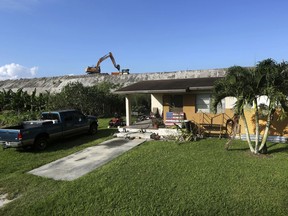 FILE - Rehabilitation work takes place on top of the Herbert Hoover Dike surrounding Lake Okeechobee, just a few feet from a home on Nov. 1, 2019, in Pahokee, Fla. Hurricane tides overtopped the original dike in 1926 and 1928, washed away houses and caused over 2,500 deaths. After 18 years, a $1.5 billion project was officially completed Wednesday, Jan. 25, 2023, to repair the sprawling dike around Florida's Lake Okeechobee that protects thousands of people from potentially catastrophic flooding during hurricanes.