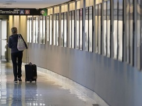 FILE - A traveler pulls their luggage between terminals at Logan International Airport, Wednesday, Jan. 11, 2023, in Boston. Airline and hotel elite status extensions due to the COVID-19 pandemic are expiring this year, and the companies are raising the requirements to earn status.