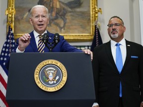 FILE - President Joe Biden speaks about student loan debt forgiveness in the Roosevelt Room of the White House, on Aug. 24, 2022, in Washington. Education Secretary Miguel Cardona listens at right. The White House is moving forward with a proposal that would lower student debt payments for millions of Americans now and in the future, offering a new route to repay federal loans under far more generous terms. Education Department officials on Tuesday, Jan. 10, 2023, called the new plan a "student loan safety net" that will prevent borrowers from getting overloaded with debt.