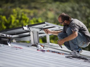 FILE - A technician installs a solar energy system at a home July 24, 2018, in Adjuntas, Puerto Rico. A U.S. government ongoing study that released preliminary results Monday, Jan. 23, 2023, has determined that with little room on the island for large-scale solar farms or wind generators, Puerto Rico should aim to reach its clean-energy goals by installing solar panels on all suitable rooftops, along with airports, brownfields and industrial areas.