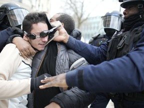 A man is detained by riot police officers during a demonstration against plans to push back France's retirement age, Tuesday, Jan. 31, 2023 in Paris. Labor unions aimed to mobilize more than 1 million demonstrators in what one veteran left-wing leader described as a "citizens' insurrection." The nationwide strikes and protests were a crucial test both for President Emmanuel Macron's government and its opponents.