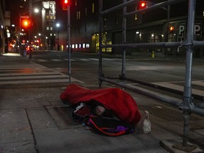A homeless man sleeps on the street, in Toronto, on Friday, March 11, 2022. Two advocates who work with Toronto's homeless community say they have observed an alarming uptick in violent physical and verbal attacks against the vulnerable population over the last several months.