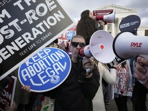 FILE - An abortion rights protestor, center, uses a megaphone as anti-abortion demonstrators rally outside the U.S. Supreme Court during the March for Life, Friday, Jan. 20, 2023, in Washington.
