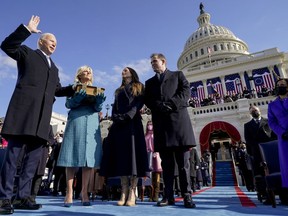 FILE - Joe Biden is sworn in as the 46th president of the United States by Chief Justice John Roberts as Jill Biden holds the Bible during the 59th Presidential Inauguration at the U.S. Capitol in Washington, Jan. 20, 2021, as their children Ashley and Hunter watch. The ocean blue tweed dress and matching coat that Jill Biden wore for Joe Biden's presidential inauguration is about to go on display at the Smithsonian's National Museum of American History. In a rare move, the museum will also display the ensemble she wore for evening inaugural events, an ivory silk wool dress and matching cashmere coat.