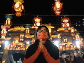 A woman wearing a face mask offers prayer at the Wong Tai Sin Temple, Saturday, Jan. 21, 2023, in Hong Kong, to celebrate the Lunar New Year which marks the Year of the Rabbit in the Chinese zodiac.