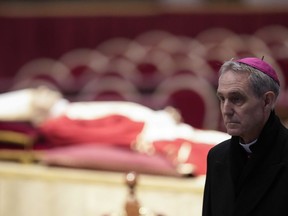 The body of late Pope Emeritus Benedict XVI laid out in state as father Georg Gaenswein stands on the right inside St. Peter's Basilica at The Vatican, Monday, Jan. 2, 2023.