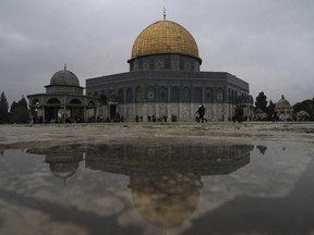 The Dome of the Rock Mosque is reflected in rainwater as worshippers gather for Friday prayers on a cold, rainy day at the Al-Aqsa Mosque compound in the Old City of Jerusalem, Friday, Jan. 6, 2023.