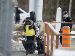 An asylum seeker crosses the border from New York into Canada followed by a Royal Canadian Mounted Police (RCMP) officer at Roxham Road in Hemmingford, Quebec, Canada March 18, 2020.  REUTERS/Christinne Muschi