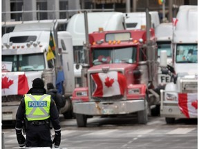 A police officer stands guard near trucks participating in a blockade of downtown streets near the parliament building as a demonstration led by truck drivers protesting vaccine mandates continues on February 16, 2022 in Ottawa, Ontario, Canada Prime Minister Justin Trudeau has invoked the Emergencies Act for the first time in Canada's history to try to put an end to the blockade which is now in it's third week.