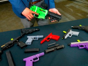 An officer with the Firearms Investigative Unit displays some of the 3D guns police have seized in Calgary, on Jan. 19.