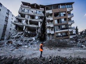 A rescue worker walks past partially collapsed buildings in the city of Antakya on February 19, 2023.