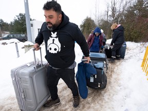 A family of asylum seekers from Colombia crosses the border at Roxham Road into Canada, Thursday, February 9, 2023 in Champlain, NY.  THE CANADIAN PRESS/Ryan Remiorz