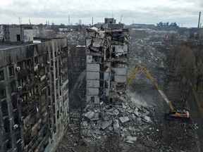 An excavator demolishes a multi-storey apartment block, which was destroyed in the course of Russia-Ukraine conflict in Mariupol, Russian-controlled Ukraine, February 15, 2023. REUTERS/Alexander Ermochenko