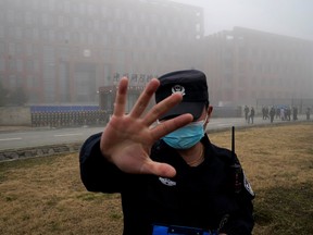 In this Feb. 3, 2021, file photo, a security person moves journalists away from the Wuhan Institute of Virology after a World Health Organization team arrived for a field visit.