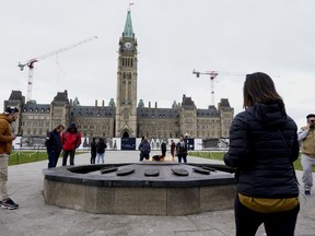 Visitors and tourists to Parliament Hill stand around the Centennial flame on Parliament Hill in Ottawa on Friday, Oct. 22, 2021.