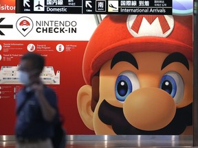 FILE - A traveler walks past an advertisement featuring a Nintendo character at Narita airport in Narita near Tokyo Friday, June 10, 2022. Japanese video game maker Nintendo recorded a slight drop in in profit in April to December 2022 as it maintained strong sales of its Switch console games.