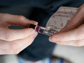 A person with Type 1 diabetes holds a vial of insulin.