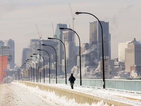 A person jogs next to a backdrop of the Montreal skyline as ice fog rises off the St. Lawrence River in Montreal, Saturday, Jan. 22, 2022. An extreme cold weather warning is in effect for Montreal, with temperatures forecast to dip to -27 C by Friday night, increasing the risk of frostbite and hypothermia, especially for the city's vulnerable homeless population.