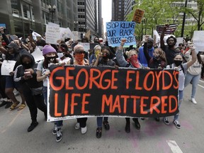 FILE - Protesters hold signs as they march during a protest over the death of George Floyd in Chicago, May 30, 2020. Candid, a leading philanthropy research group, is leading a coalition of funders and grantees that want to standardize the collection of demographic information to help target donations to minority-led groups. Corporations and foundations pledged billions for racial equity after the police killing of Floyd in 2020. But statistics show that philanthropic money flows unequally to white-led and minority-led organizations.