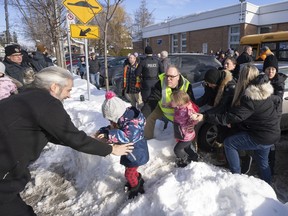 Parents and their children are loaded onto a warming bus as they wait for news after a bus crashed into a daycare centre in Laval, Que., Wednesday, Feb. 8, 2023.