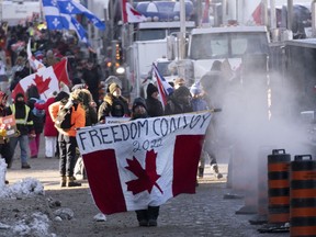 Protesters participating in a cross-country truck convoy protesting measures taken by authorities to curb the spread of COVID-19 and vaccine mandates walk near Parliament Hill in Ottawa on Saturday, Jan. 29, 2022. The City of Ottawa's auditor general says key decisions in response to the "Freedom Convoy" were made among select members of the city's oversight body which only met once throughout the weeks-long protests.