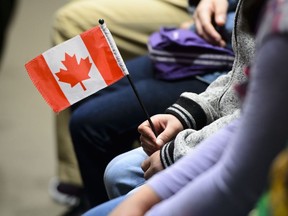 A young new Canadian holds a flag as she takes part in a citizenship ceremony on Parliament Hill in Ottawa on Wednesday, April 17, 2019.