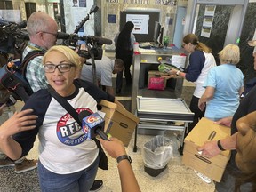 Eileen Carter, an organizer of a recall petition drive against New Orleans Mayor LaToya Cantrell, holds a box of petitions as others are put through security equipment at New Orleans City Hall on Wednesday, Feb. 22, 2023. Organizers say they have enough signatures to force a recall referendum on Cantrell.