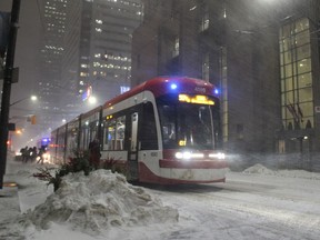 Commuters board a TTC streetcar in Toronto's downtown core as a winter storm starts to hit the city on Monday, Feb. 27, 2023. The chief executive of the Toronto Transit Commission is asking for more emergency spending authority, which could be used to extend contracts for 50 temporary security guards brought on in the wake of a number of violent transit incidents.