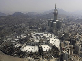 FILE - The Abraj Al-Bait Towers with the four-faced clocks stands over the holy Kabaa, as Muslims encircle it inside the Grand Mosque during the annual pilgrimage, known as the hajj, in the Muslim holy city of Mecca, Saudi Arabia, on Oct. 5, 2014. A criminal court has imposed a $5.3 million fine on the Saudi BinLadin Group and sentenced seven people to prison over the collapse of a crane ahead of the 2015 hajj pilgrimage that killed more than 100 people, a leading Saudi daily reported Tuesday, Feb. 14, 2023.
